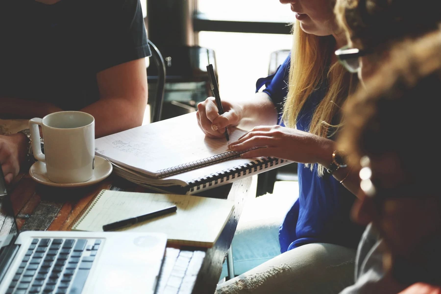 People collaborating over notebooks at a table.