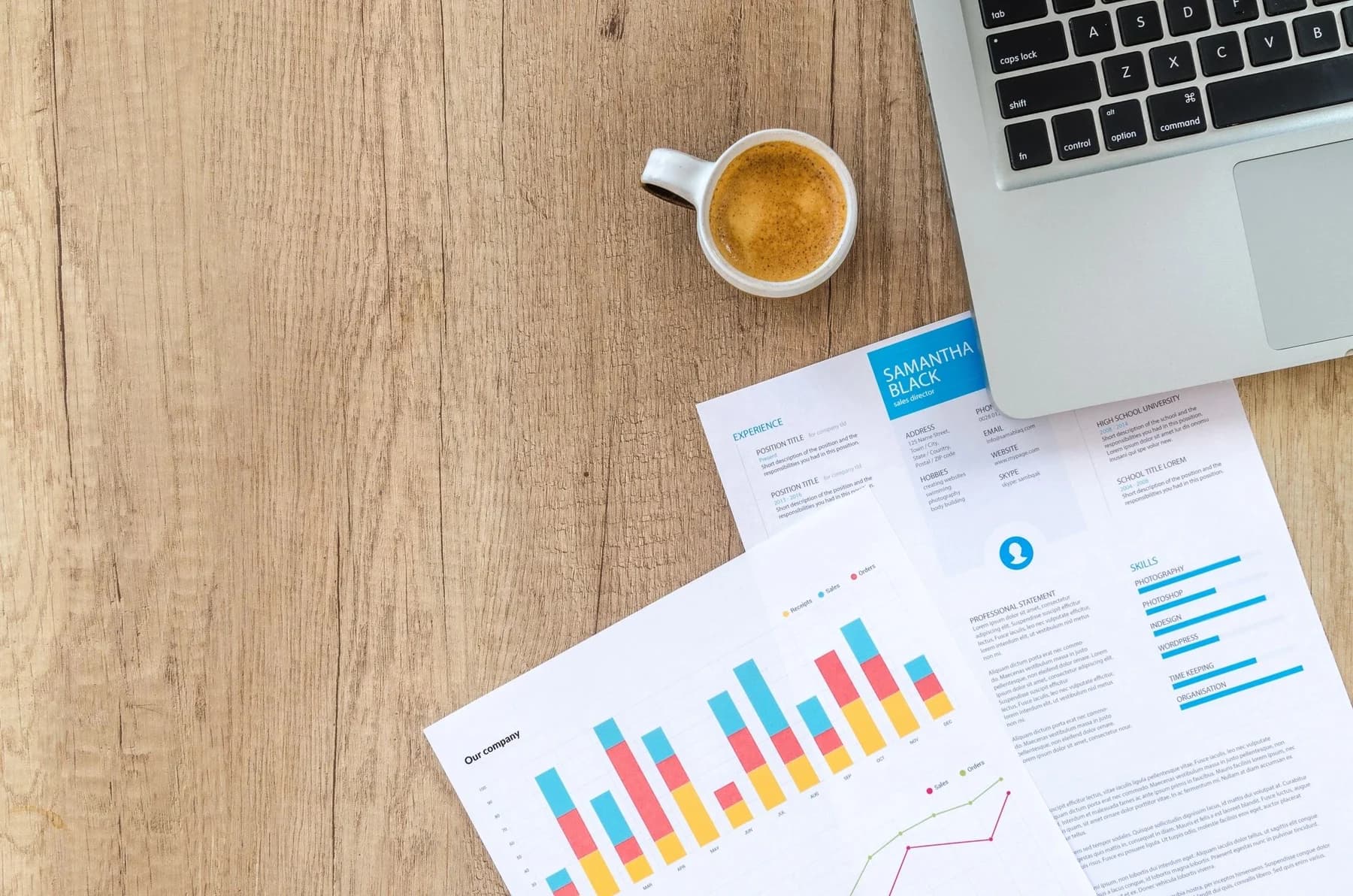 A laptop, coffee, and printed charts on a desk.